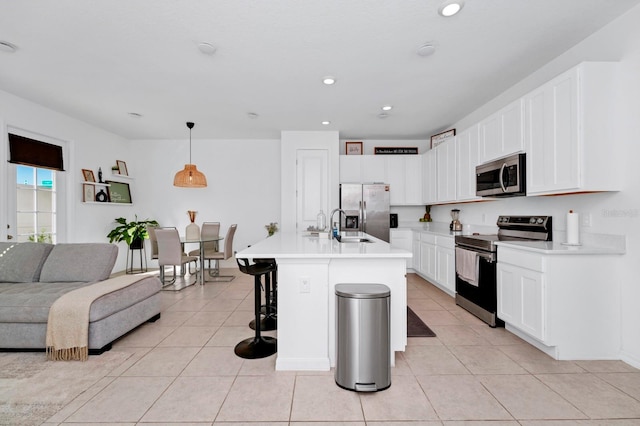 kitchen with a center island with sink, decorative light fixtures, light tile floors, a breakfast bar, and appliances with stainless steel finishes