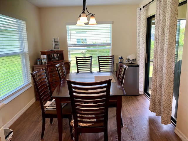 dining area with dark wood-type flooring and a notable chandelier