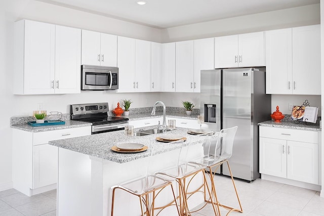 kitchen featuring a breakfast bar area, white cabinetry, stainless steel appliances, and a sink