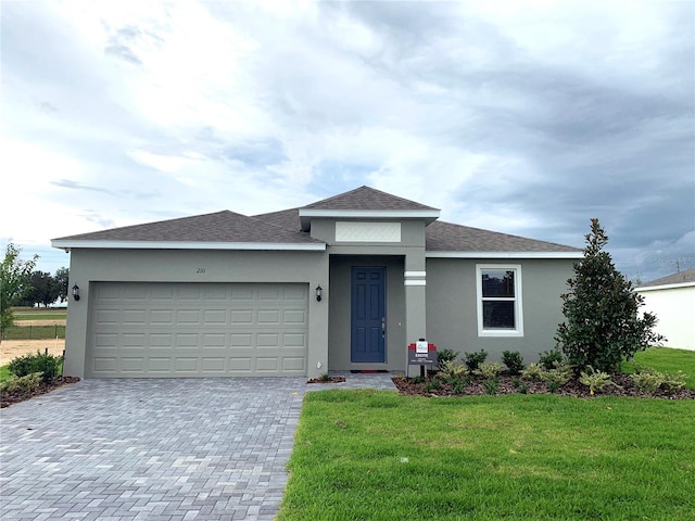 view of front of home with a front yard, roof with shingles, an attached garage, stucco siding, and decorative driveway