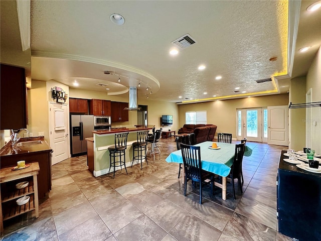 dining area with light tile floors, sink, and a textured ceiling