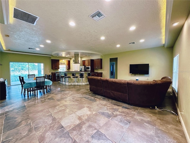 tiled living room with crown molding and a textured ceiling