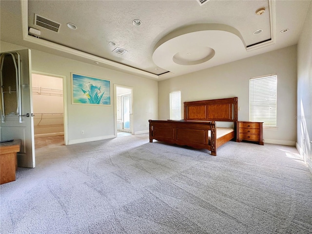 unfurnished bedroom with carpet flooring, a spacious closet, a tray ceiling, and a closet