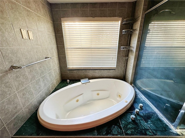 bathroom with tile walls and a tub