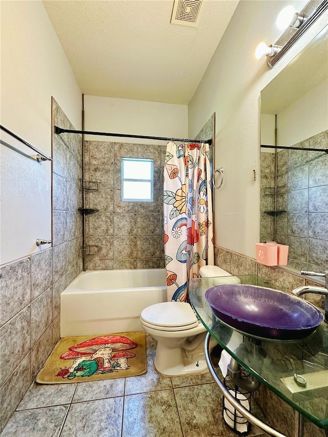 full bathroom featuring tile flooring, shower / bath combination with curtain, toilet, and a textured ceiling