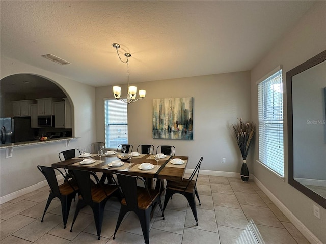 tiled dining room featuring an inviting chandelier, a textured ceiling, and a wealth of natural light