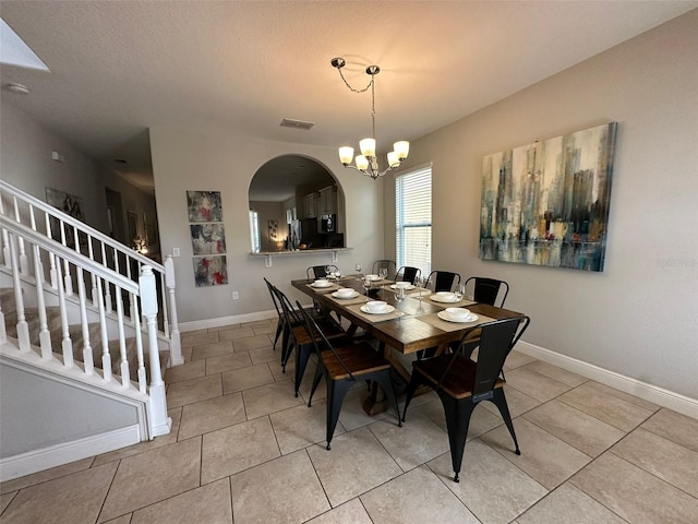 tiled dining room featuring an inviting chandelier and a textured ceiling