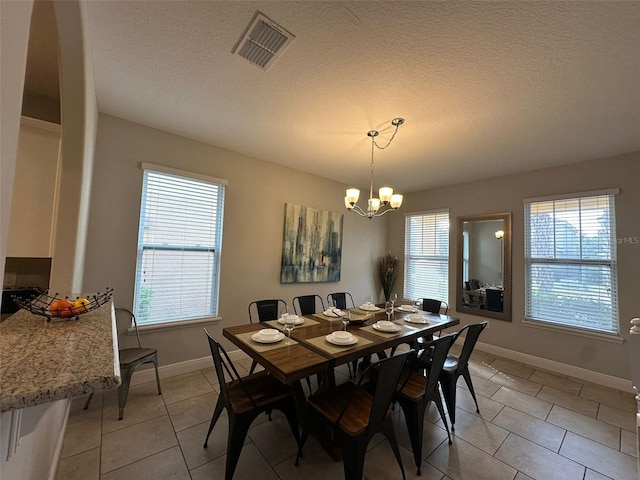 tiled dining space featuring a chandelier and a textured ceiling