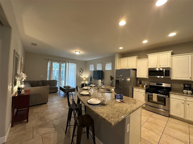 kitchen featuring stainless steel appliances, a kitchen island with sink, and white cabinets