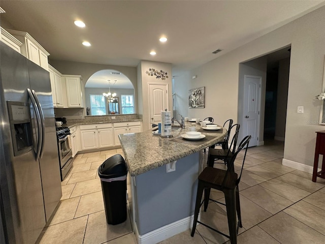 kitchen featuring light tile patterned flooring, an island with sink, white cabinetry, a kitchen breakfast bar, and stainless steel appliances