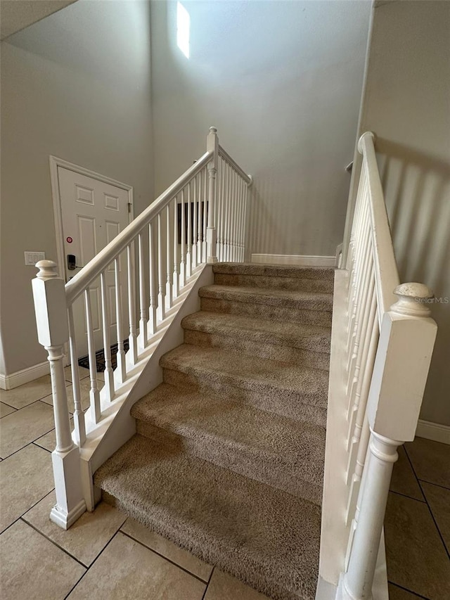 stairs featuring a high ceiling and tile patterned flooring