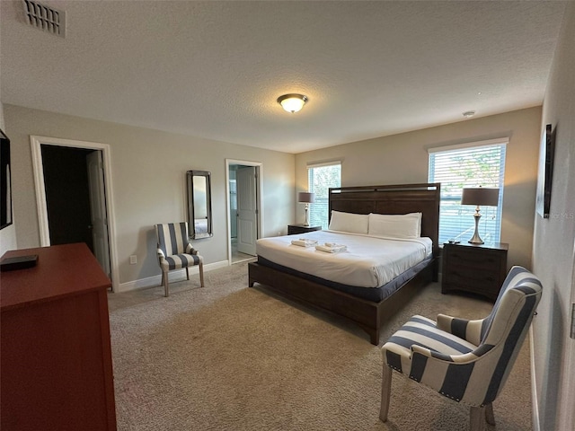 carpeted bedroom with connected bathroom and a textured ceiling