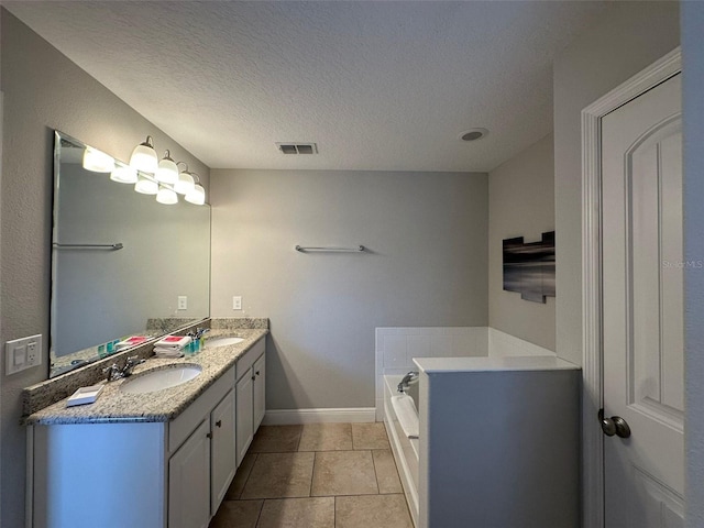 bathroom with vanity, a tub to relax in, tile patterned flooring, and a textured ceiling