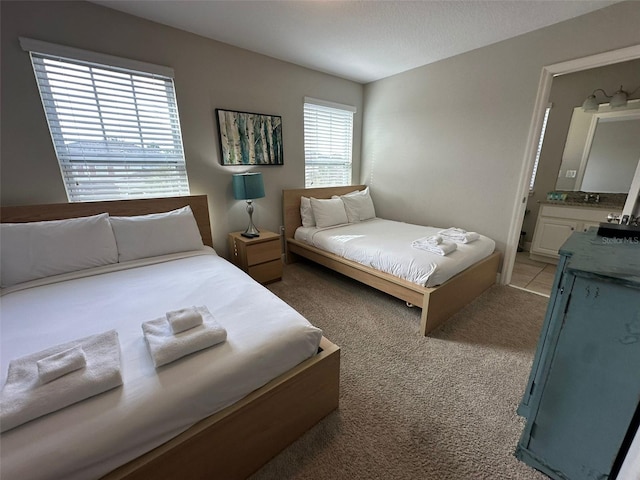 bedroom featuring ensuite bath and light carpet