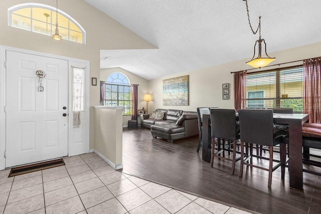 tiled entrance foyer featuring a textured ceiling, vaulted ceiling, and plenty of natural light