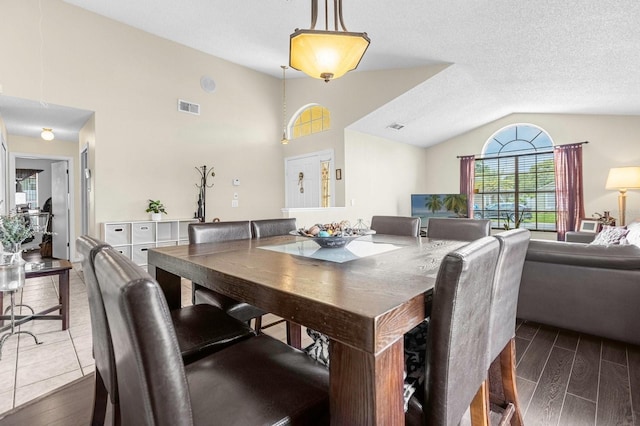 dining space with a textured ceiling, lofted ceiling, and hardwood / wood-style flooring