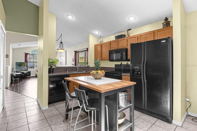 kitchen with black appliances, butcher block countertops, light tile patterned flooring, and a kitchen island