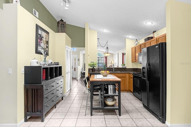 kitchen with vaulted ceiling, black appliances, kitchen peninsula, sink, and light tile patterned flooring