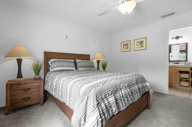 bedroom with sink, ensuite bath, ceiling fan, and light colored carpet