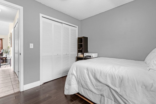 bedroom with a closet, a textured ceiling, and dark hardwood / wood-style floors