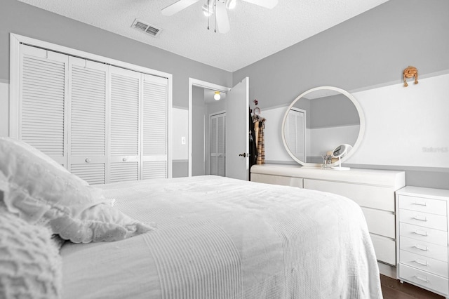 bedroom with a textured ceiling, ceiling fan, and dark hardwood / wood-style flooring