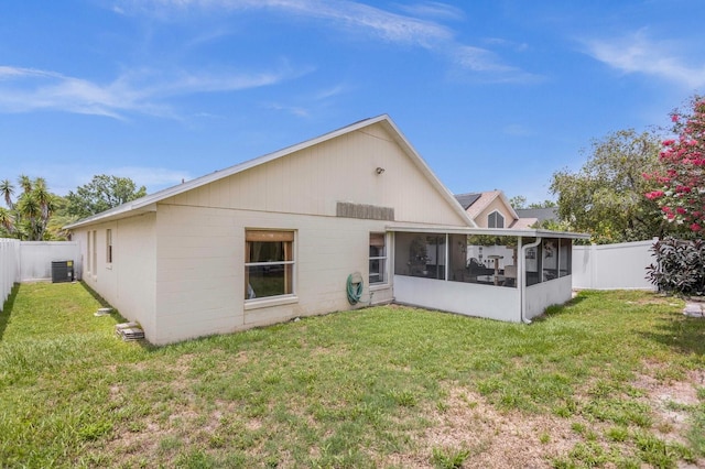 rear view of property featuring a yard, central AC, and a sunroom