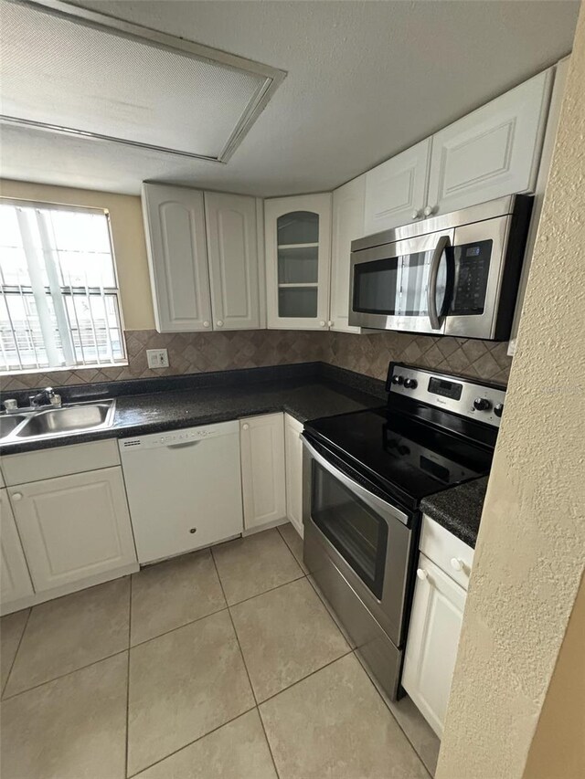 kitchen with white cabinetry, light tile patterned flooring, backsplash, and stainless steel appliances