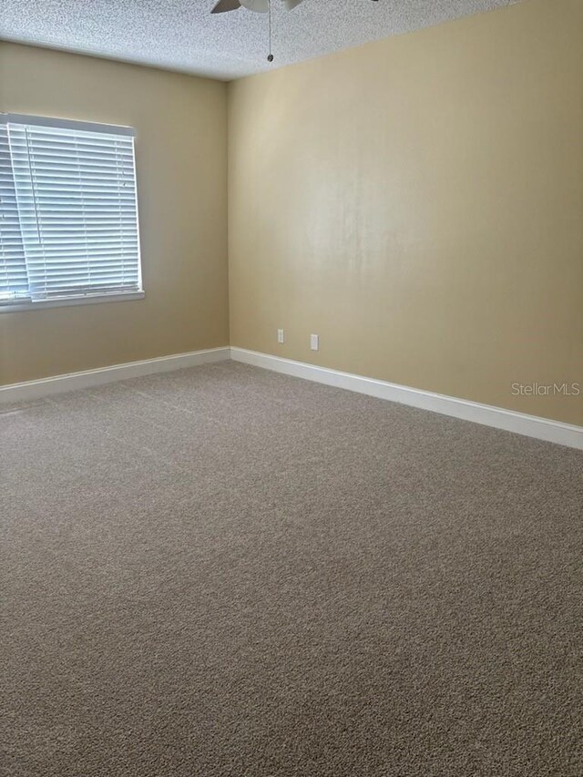 empty room with ceiling fan, carpet flooring, and a textured ceiling