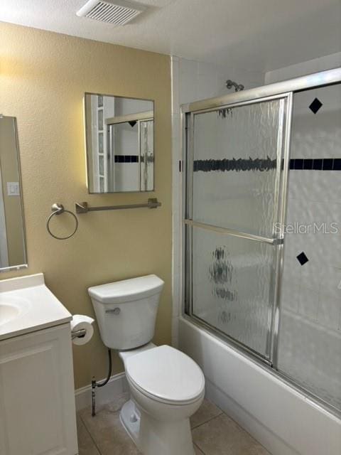 full bathroom featuring vanity, combined bath / shower with glass door, toilet, and tile patterned floors