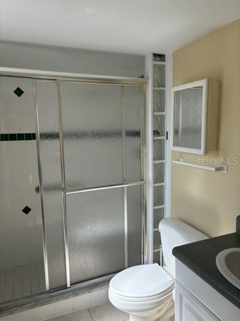 bathroom with vanity, toilet, tile patterned floors, and walk in shower