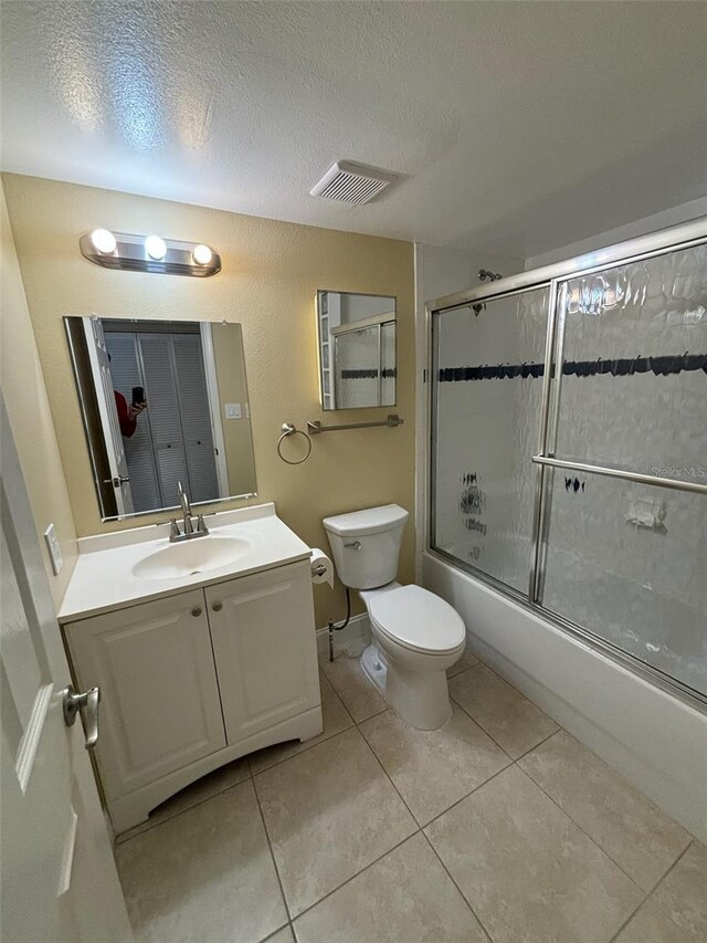 full bathroom with tile patterned flooring, enclosed tub / shower combo, a textured ceiling, toilet, and vanity