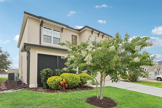 view of front of home featuring a garage, a front lawn, and central air condition unit