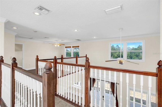 hall featuring a textured ceiling, ornamental molding, and carpet floors