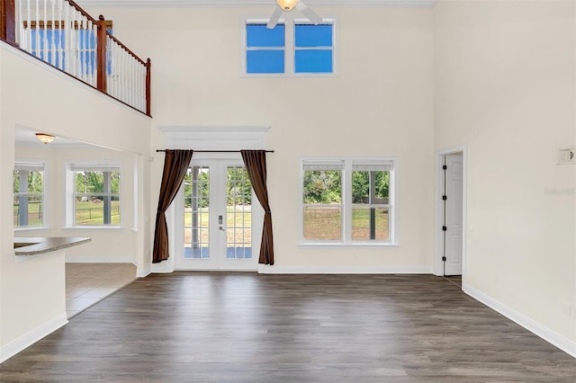 unfurnished living room with french doors, ceiling fan, dark wood-type flooring, and a high ceiling