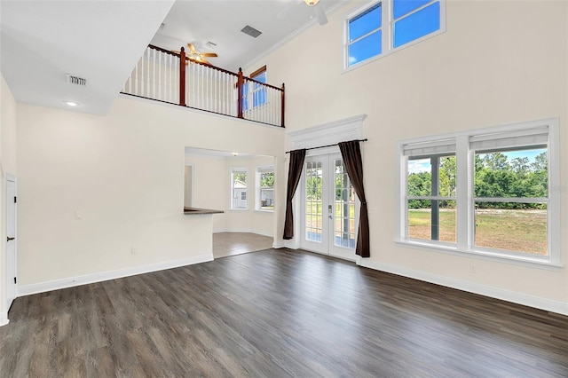 unfurnished living room with crown molding, ceiling fan, a high ceiling, and dark hardwood / wood-style floors