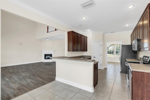 kitchen featuring light hardwood / wood-style flooring, ornamental molding, a textured ceiling, appliances with stainless steel finishes, and kitchen peninsula