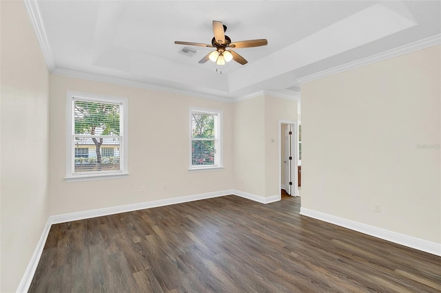 empty room with a raised ceiling, ceiling fan, dark wood-type flooring, and ornamental molding