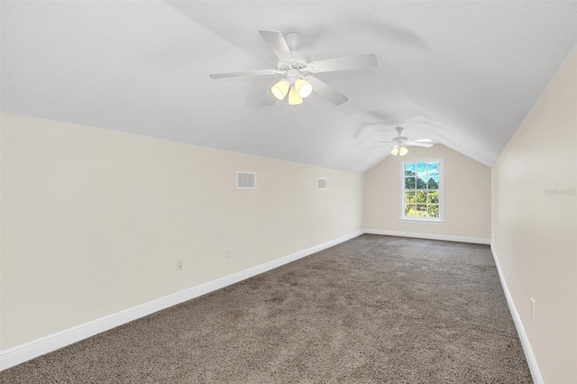 additional living space featuring dark colored carpet, ceiling fan, and vaulted ceiling