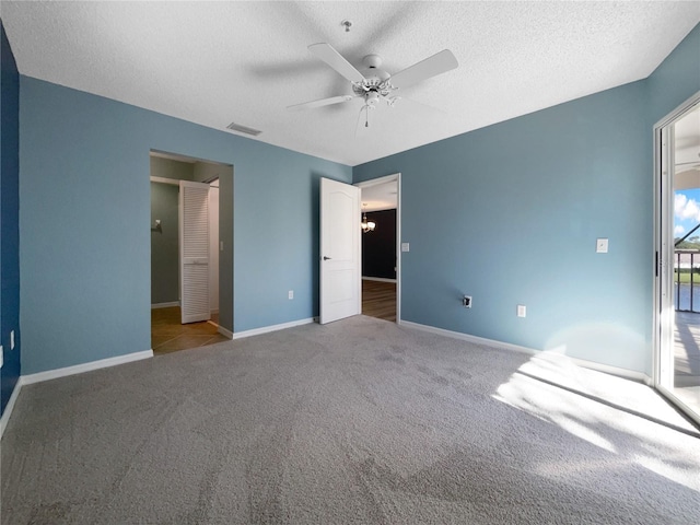 unfurnished bedroom featuring ceiling fan with notable chandelier, a textured ceiling, and light carpet