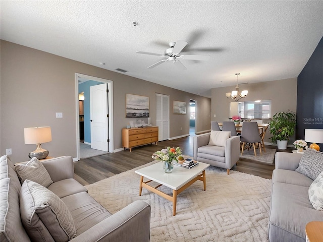 living room featuring wood-type flooring, ceiling fan with notable chandelier, and a textured ceiling