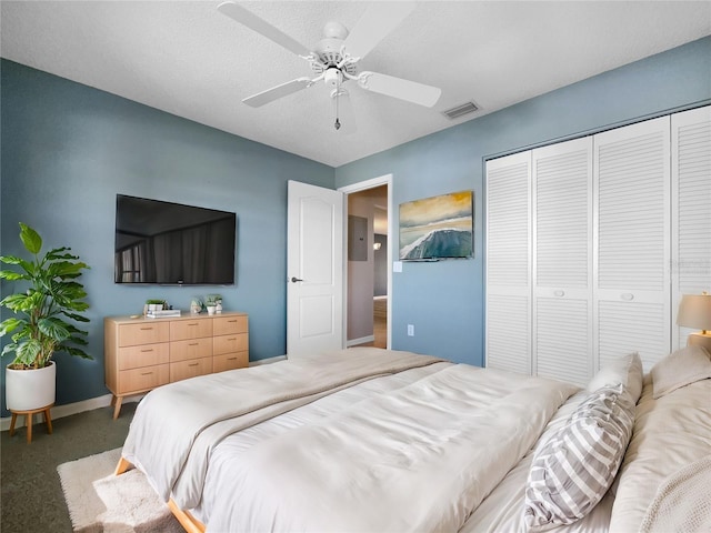 bedroom with ceiling fan, a closet, a textured ceiling, and dark colored carpet