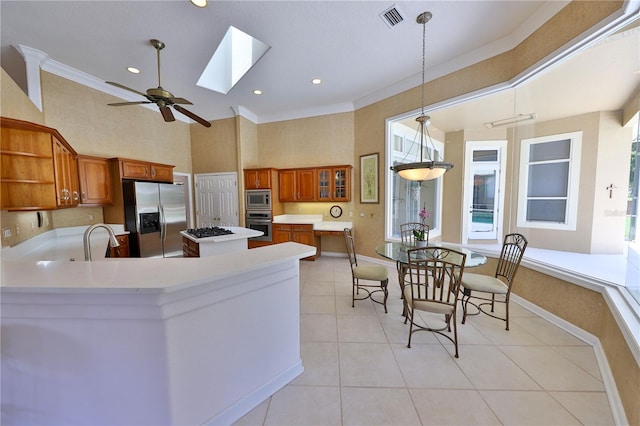 kitchen featuring kitchen peninsula, a skylight, stainless steel appliances, crown molding, and decorative light fixtures