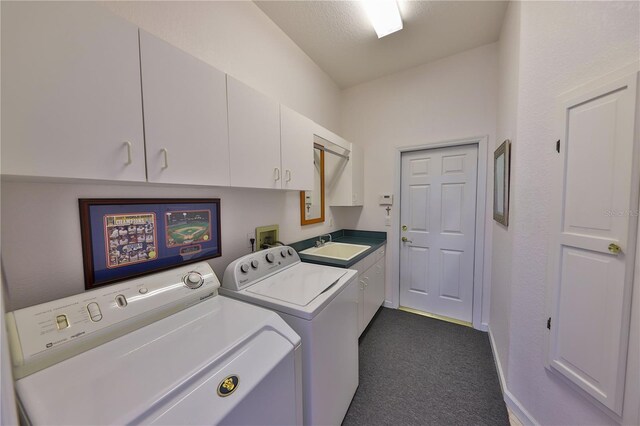 clothes washing area with cabinets, dark carpet, a textured ceiling, sink, and washer and dryer