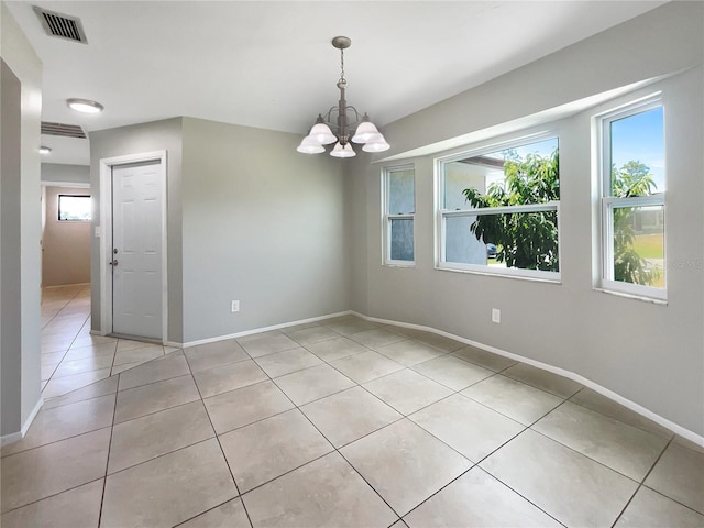 tiled empty room featuring a notable chandelier