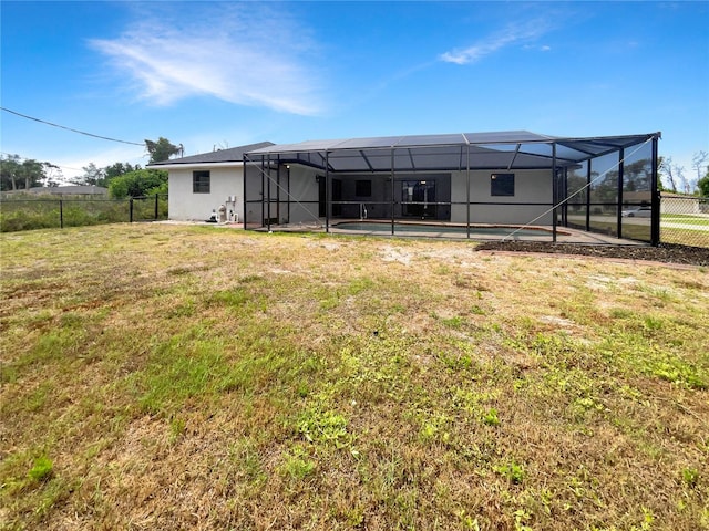 back of property with a lanai, a yard, and a fenced in pool