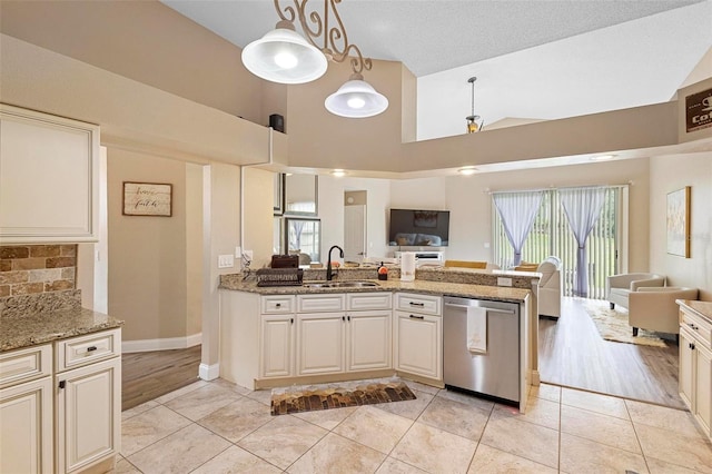 kitchen with light stone countertops, stainless steel dishwasher, sink, decorative light fixtures, and light hardwood / wood-style floors