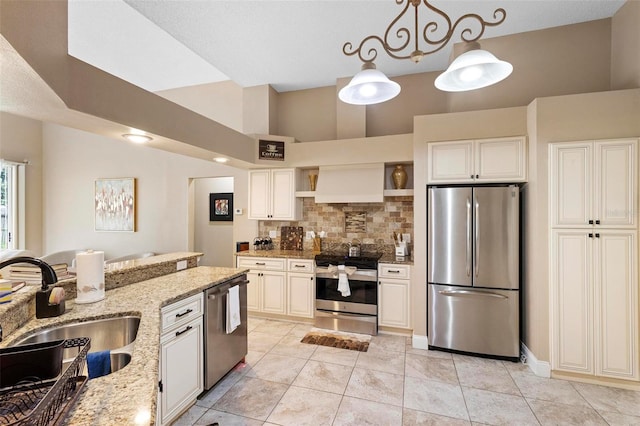 kitchen featuring appliances with stainless steel finishes, light stone counters, custom exhaust hood, sink, and hanging light fixtures