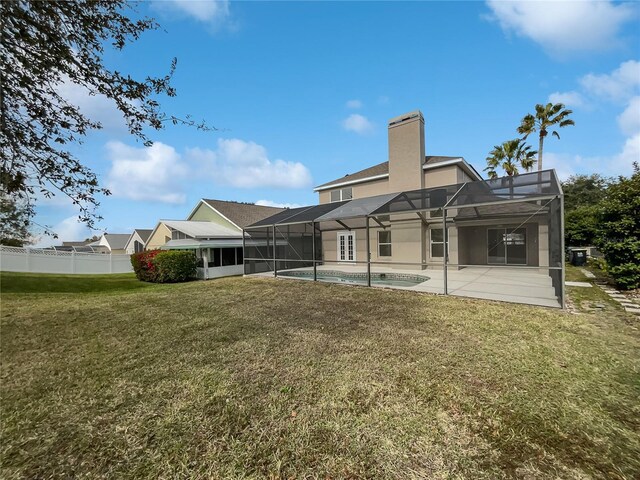 rear view of house featuring a lanai, a lawn, a patio, and a fenced in pool