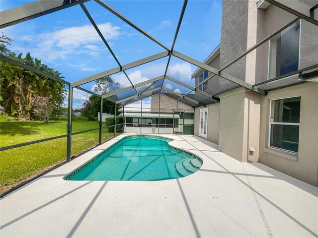 view of pool with a lanai, a patio area, and a yard