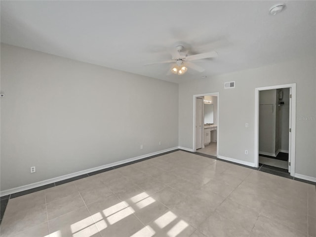 unfurnished bedroom featuring connected bathroom, a spacious closet, ceiling fan, a closet, and light tile patterned floors